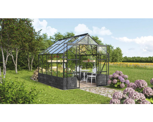 Gewächshaus mit Stahlrahmen, Glaseinsätzen und Fundament auf einer Wiese mit Gartenmöbeln