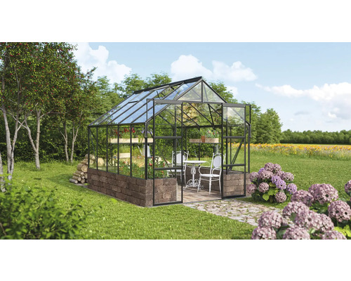 Gewächshaus mit Stahlrahmen, Steinbasis, Pflanzen, Tisch und Stühlen in einem Garten