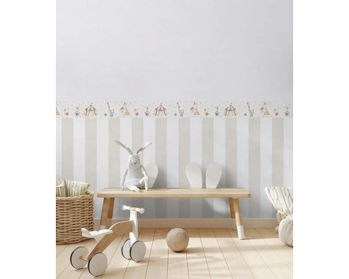Kinderzimmer mit gestreifter Tapete und Zirkusmotivbordüre, mit Holzbank, Spielzeug und Dekoration