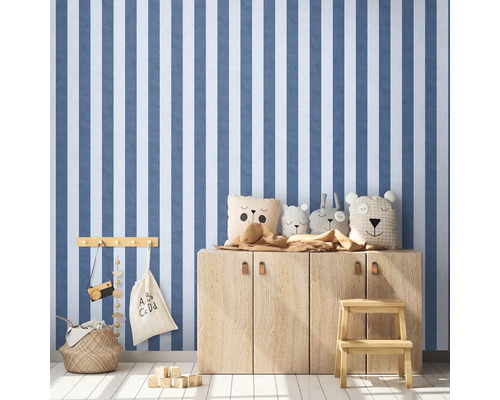 Kinderzimmer mit gestreifter Tapete, Holzkommode und Spielsachen.