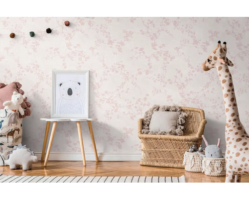 Kinderzimmer mit blütenmusterbedruckter Tapete, Rattanmöbeln und Stofftieren.