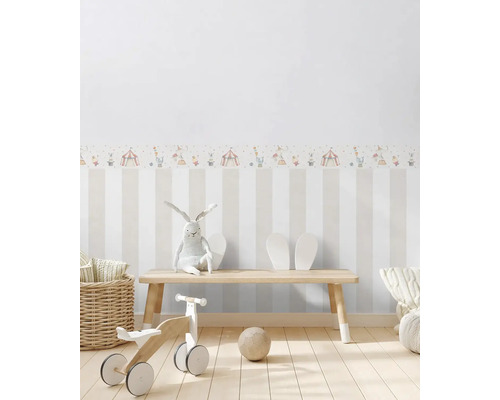 Kinderzimmer mit gestreifter Tapete, Zirkusbordüre, Spielzeug und Holzbank.