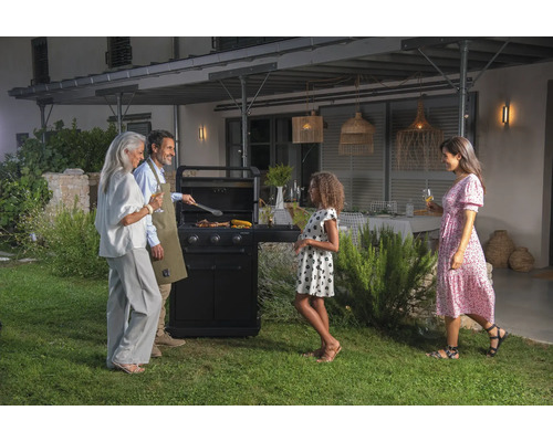Eine Familie grillt zusammen im Garten mit einem Gasgrill.