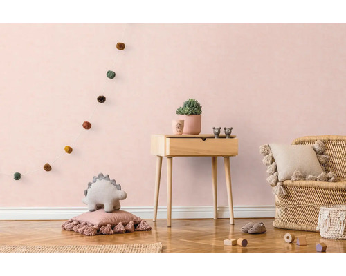 Kinderzimmer mit Holzkommode, Rattansessel und dekorativen Elementen