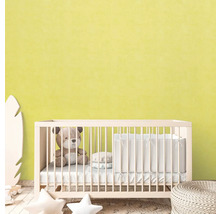 Babyzimmer mit Gitterbett, Teddybär und Deko-Elementen vor hellgelber Wand