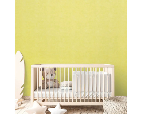 Babyzimmer mit Gitterbett, Teddybär und Deko-Elementen vor hellgelber Wand