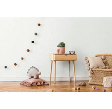 Kinderzimmer mit Holzkommode, Rattansessel und Dekorationsartikeln