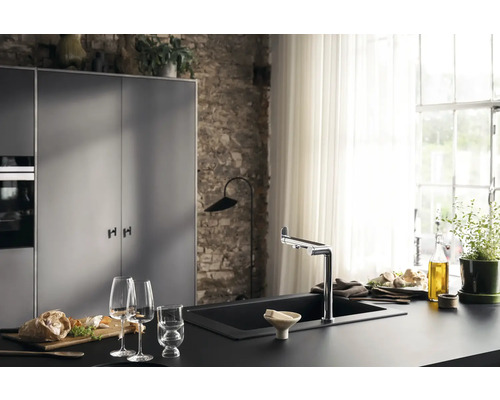 Moderne Küche mit schwarzer Arbeitsplatte, Spüle und Armatur vor einer Steinwand