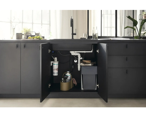 Küchenspüle mit geöffnetem Unterschrank, der einen Abfalleimer, einen Wasserfilter und Reinigungsutensilien zeigt.