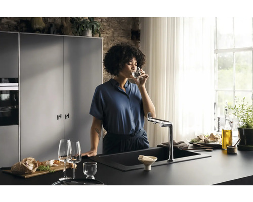 Moderne Küche mit Spüle, Armatur und einer Frau, die ein Glas Wasser trinkt