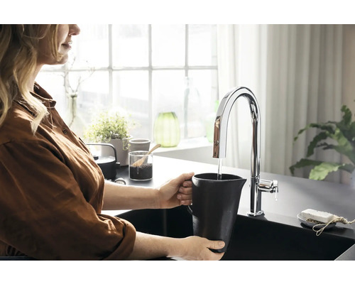 Frau befüllt Kanne am Wasserhahn in der Küche