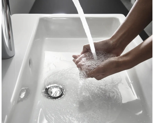 Händewaschen im weißen Keramikwaschbecken mit Wasserhahn