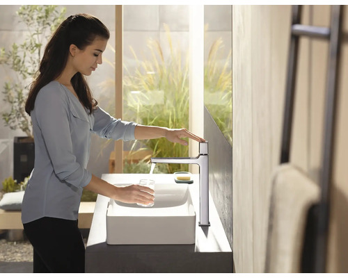 Frau befüllt Glas am Waschbecken mit Wasserhahn im Badezimmer