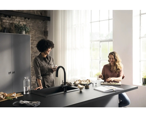 Helle Küche mit zwei Frauen an einer Küchentheke mit Spüle und Armatur, Geschirr, Zutaten und Küchenutensilien.