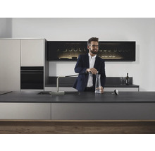 Moderne Küche mit Spender, Spüle und stilvollem Mann