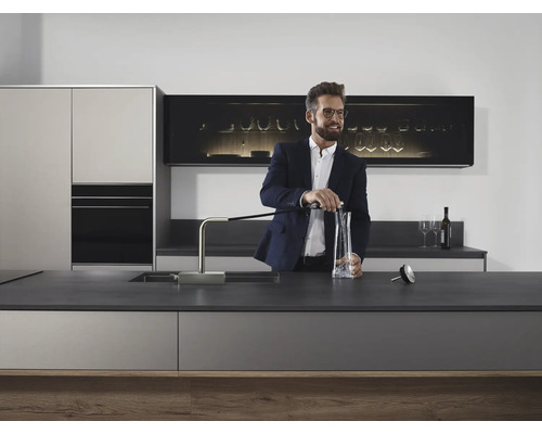 Moderne Küche mit Spender, Spüle und stilvollem Mann