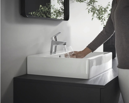 Modernes Badezimmer mit rechteckigem Waschbecken, Armatur und Person, die ein Glas Wasser füllt