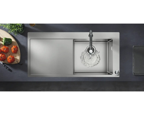 Spültisch aus Edelstahl mit Abtropffläche, Wasserhahn und frischem Gemüse