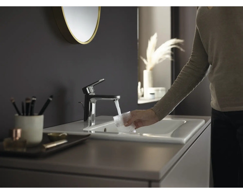 Modernes Badezimmer mit Waschbecken, Armatur und Person, die ein Glas Wasser einfüllt
