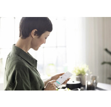 Frau benutzt ein Smartphone in einem hellen Raum für Online-Shopping.