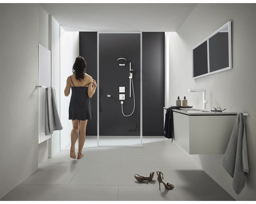 Helles Badezimmer mit Dusche, Waschbeckenunterschrank, Spiegel und Heizkörper.