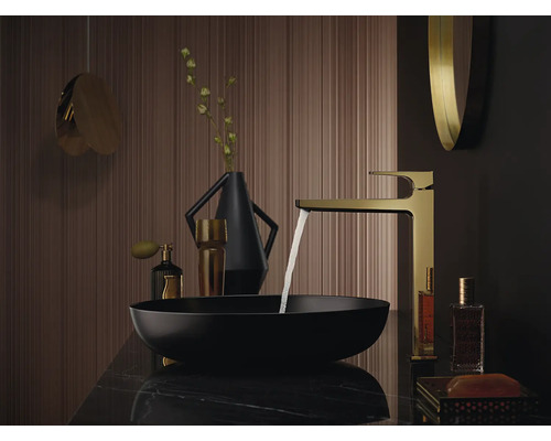 Badezimmerwaschtisch mit goldener Armatur, schwarzem Aufsatzwaschbecken und dekorativen Elementen