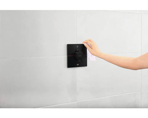 Hand reinigt Thermostatbatterie im Badezimmer