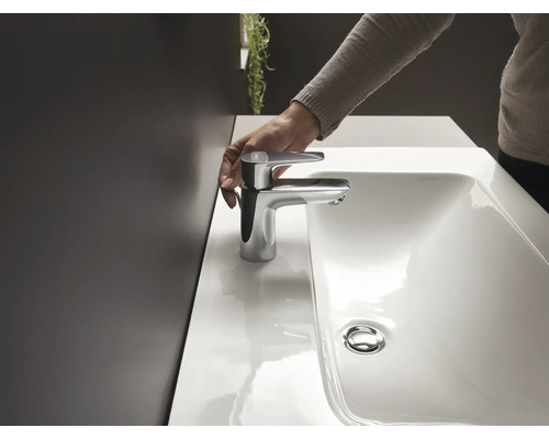 Person bedient ein Waschbecken mit Chromarmatur