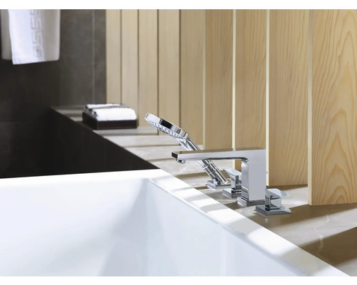 Moderne Badewanne mit verchromter Armatur und Handbrause vor einer Holzverkleidung