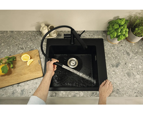 Schwarze Küchenspüle mit ausziehbarer Armatur im modernen Design auf einer Arbeitsplatte, während Wasser in das Spülbecken läuft.