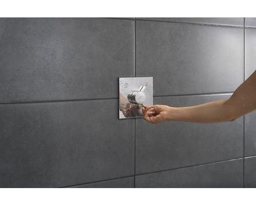 Aufputz-Brausethermostat mit Bedienung durch eine Person an einer gefliesten Wand