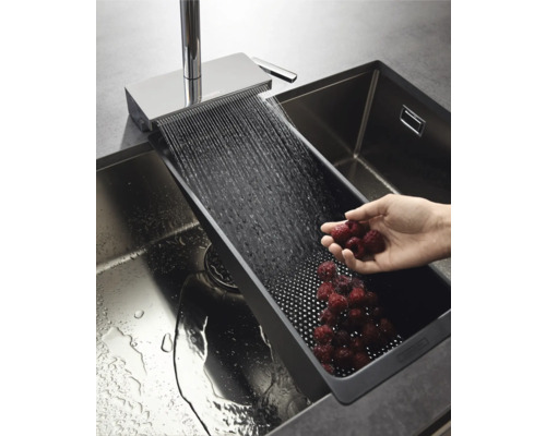 Küchenspüle mit Abtropfschale und Wasserhahn beim Waschen von Himbeeren