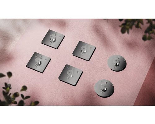 Mehrere Hansgrohe Fertigsets für Badarmaturen auf rosafarbenem Grund