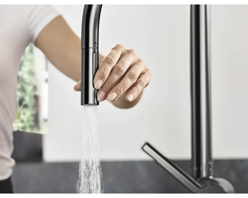 Frau bedient eine Küchenarmatur mit Wasserauslauf