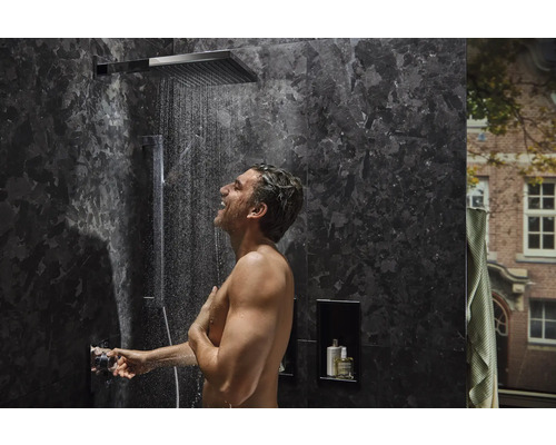 Mann unter einer Regendusche in einem modernen Badezimmer mit dunklen Marmorfliesen