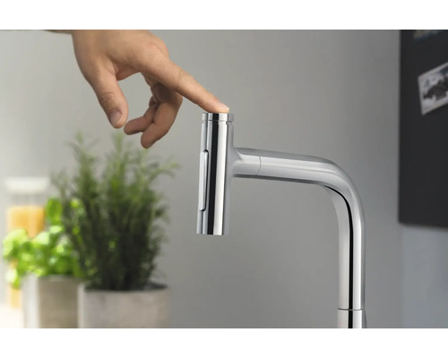 Eine Hand betätigt einen Küchenarmatur-Druckknopf, um den Wasserfluss zu steuern.