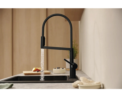 Schwarzer Küchenarmatur mit Wasserstrahl über einer Spüle