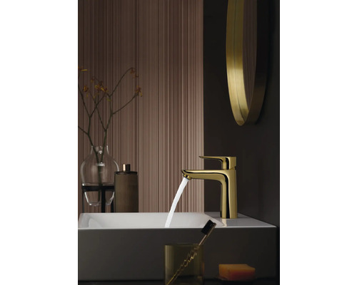Goldene Waschtischarmatur im Badezimmer mit Waschbecken und Accessoires