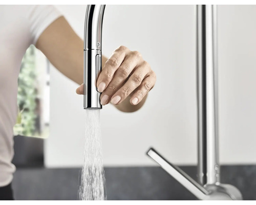 Frau bedient eine Küchenarmatur mit Wasserauslauf.