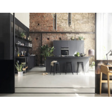 Helle Küche im Loftstil mit Kücheninsel, Barhockern und Regalen vor einer Backsteinwand.