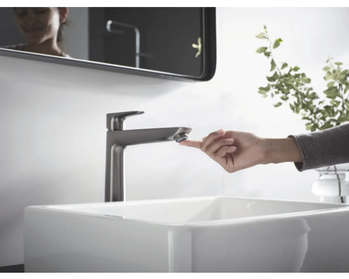 Waschbecken mit Armatur und berührender Hand im Badezimmer