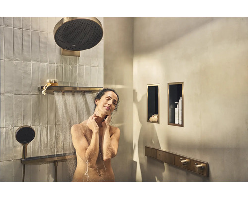 Frau unter einer Duscharmatur mit Kopfbrause und Handbrause in einem Badezimmer