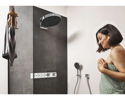 Moderne Dusche mit Kopfbrause, Handbrause und Armaturen sowie eine Frau, die in ein Handtuch gehüllt ist