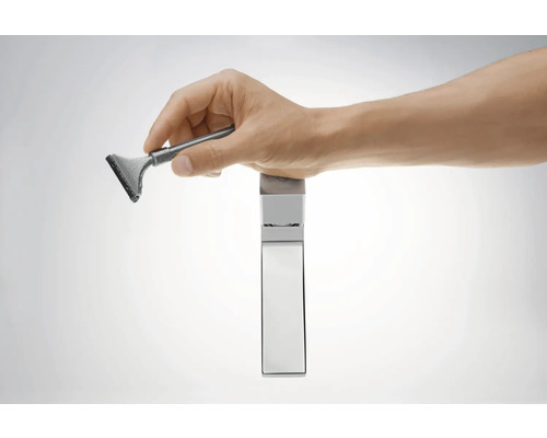 Hand hält Fensterabzieher über einem Wasserhahn