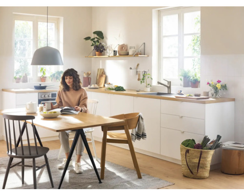 Helle Küche mit Esstisch und sitzender Person