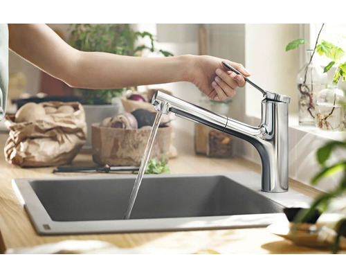 Person bedient eine Küchenarmatur aus Chrom über einem Spülbecken.