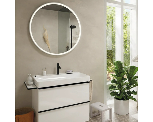 Badezimmer mit Waschtisch, rundem Spiegel mit Beleuchtung und Zimmerpflanze