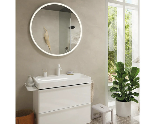 Badezimmer mit rundem Spiegel mit Beleuchtung, Waschbeckenunterschrank und Zimmerpflanze