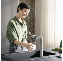Frau befüllt Glas mit Wasserhahn an Spüle