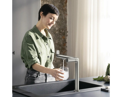 Frau befüllt Glas mit Wasserhahn an Spüle